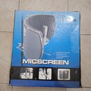 Modrá krabice s produktovou fotografií akustického stínidla pro mikrofon. Na obalu je svisle napsáno MICSCREEN a v horní části text Musikhaus Thomann…