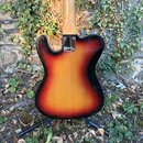 Zadní strana elektrické kytary s tělem v červeno-žlutém sunburst provedení. Na kovovédesce u krku je nápis MADE IN USA. Povrch laku vykazuje drobné š…