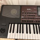 Černý klavír s nápisem KORG a modelem Pa700 PROFESSIONAL ARRANGER. Nástroj má ovládací panel s několika tlačítky, posuvníky a displejem TouchView. Na…