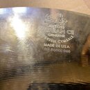 Detailní záběr na povrch kovového činely zlatavé barvy s viditelným broušením. Na povrchu je vyražen nápis: AVEDIS ZILDJIAN Co GENUINE TURKISH CYMBAL…