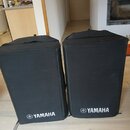 Dvě černé textilní kryty na reproduktory nebo komba. V dolní části obou krytů je bílý nápis YAMAHA s doprovodným logem. Povrch materiálu je matný a v…