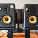 Pár černých studiových monitorů s žlutými membránami basových reproduktorů. Na obou je vidět nápis V6 a logo KRK SYSTEMS. Levý reproduktor má v horní…