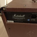 Zadní strana hnědého kytarového komba s texturovaným povrchem. Na černé štítku je bílý nápis Marshall a text: Designed, Engineered & Quality Controll…
