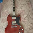 Elektrická kytara s červeným trupem a černým hracím hnedem. Na hlavě je viditelné logo Gibson. Nástroj má dva humbuckery, čtyři ovládací knoflíky a č…