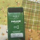 Zadní strana zeleného kytarového efektu. Na povrchu jsou bílé nápisy: „9VDC 10mA“, logo „NUX MINI CORE“, značka „CE“ s přeškrtnutou koší, web „www.nu…