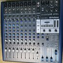 Stříbrnošedý mixážní pult s modrým rámem a nápisem STUDIOLIVE AR12c a logem PreSonus. Zařízení obsahuje několik vstupních kanálů s knoflíky pro zisk,…