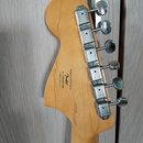 Zadní strana hlavy kytary z přírodního světlého dřeva s chromovanými ladičkami. Na dřevě je černý nápis: Designed and Backed by Fender S/N ICSH203154…