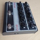 Kytarový předzesilovač s černým šasi a stříbrným ovládacím panelem. Na panelu je nápis FRIEDMAN, model IR-D a text CURL TUBE PREAMP. Jsou zde tři sto…
