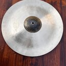 Kruhové činely z kovového materiálu s matným povrchem a tmavším středem. Na levé straně je viditelné logo Meinl. Povrch vykazuje drobné nečistoty a z…