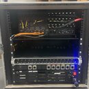 Zadávací rack v hliníkovém flightcase obsahuje několik zařízení s rozhraními pro audio a data. Horní jednotka má nápisy POWER, DIGITAL AUDIO NETWORK,…