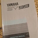 Bílá tištěná příručka s nápisy YAMAHA, MUSIC SYNTHESIZER a SY99. Ve spodní části je černý pruh s textem OPERATING MANUAL. Papír vykazuje známky opotř…