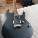 Černá elektrická kytara s matným povrchem a hnědým hmatníkem. Nástroj má dva humbuckery, jeden ovládací knoflík hlasitosti a jeden tón. Na těle jsou…