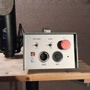 Na fotografii je černý mikrofon s kovovou mřížkou a stříbrný ovládací box. Na boxu jsou nápisy HPF FREQ (s přepínačem 80Hz, OFF, 40Hz), GAIN (s přepí…