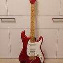 červená elektrická kytara s jasným lakem a hnědým hmatníkem. Na hlavě je zlatý nápis Ibanez a na těle se nachází bílý pickguard s třemi snímači. Kyta…