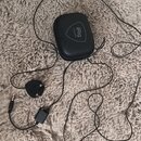 Na fotografii je černý přenosný audio rozhraní iRig s připojeným kabelem a konektorem jack. Součástí je černý zipový obal s bílým nápisem iRig Acoust…