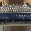 Míchací pult značky Soundcraft umístěný v transportním kufru. Zařízení má modré tělo s bílým logem Soundcraft a řadu ovládacích prvků v podobě posuvn…