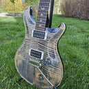 Elektrická kytara s tělem z plaménkového dřeva v přírodním odstínu. Nástroj má dva humbuckery, hrazdý most s páčkou a jeden ovládací knoflík. Na hmat…