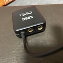 Černý obdélníkový modul s nápisy KORG a plugkey MOBILE MIDI/AUDIO. Na přední straně jsou dva zlaté konektory jack a jeden připojený černý kabel. Povr…