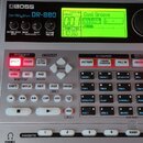 Elektronický doprovodný automat Boss Dr. Rhythm DR-880 v šedé barvě. Zařízení má podsvícený displej s nápisem Cool Groove a řadu ovládacích tlačítek,…