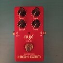 Červený kytarový efekt s nápisy nux, HG-6 a DISTORTION HIGH GAIN. Na horní straně jsou čtyři černé otočné ovířky s popisky LEVEL, GAIN, SCOOP a TONE.…