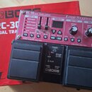 Červený pedalboard s nápisy RC-30 DUAL TRACK LOOPER a Loop Station. Zařízení má ovládací prvky pro LOOP FX, MEMORY, RHYTHM a MIC, včetně dvou černých…