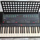 Černý elektronický klavír s nápisem YAMAHA PSR-400 a označením AWM. Nástroj má standardní klávesnici s bílými a černými klávesami, v levém dolním roh…