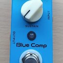 Modrý kytarový efekt s nápisem Blue Comp a značkou MOOGER. Na horní straně jsou dva černé otočné knoflíky s popisky LEVEL a ATTACK, přepínač Treble/N…