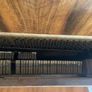 Detailní pohled do vnitřku hudebního nástroje s řadou kovových plátků a ladicích šroubků. Horní část tvoří dřevěný povrch s výraznou masivní struktur…
