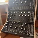 Tři černé modulační syntetizátory značky moog umístěné v dřevěném stojanu. Horní jednotka nese nápis SPECTRAVOX SEMI MODULAR SYNTHESIZER, prostřední…