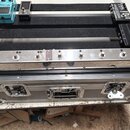 Stříbrný hliníkový kufr s černým vnitřkem, který slouží jako pedalboard. V horní části jsou umístěny tři efekty: modrý pedál s nápisem Chorus, černý…