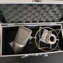 V otevřeném černém přepravním kufru s pěnovou výplní je umístěn stříbrný kondenzátorový mikrofon a odpružívalo držadlo (shock mount). Na spodní části…