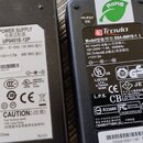 Fotografie zobrazuje dva černé napájecí adaptéry s bílými štítky. Levý adaptér nese značku UMEC a model UP0451E-12P, s výstupem +12V 3.75A a nápisem…