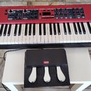Červený digitální klavír s bílými a černými klávesami. Na pravé straně je bílý nápis nord piano 5 a pod ním menší text VIRTUAL HAMMER ACTION TECHNOLO…