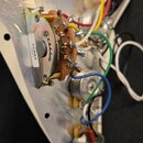 Fotografie zachycuje vnitřní elektroniku hudebního nástroje s kovovou stínící vrstvou. Je zde vidět přepínací spínač s nápisem "SUIKLON" a bílý štíte…