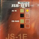 Fotografie detailu krabice od mikrofonu. Na obalu jsou viditelné nápisy JSB-1E91, JS-1E a CX-509, dále text Budget Large Diaphragm Studi a The JS-1E…
