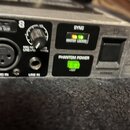 Detailní záběr na přední panel černého elektronického zařízení v kovovém šasi. Jsou vidět vstupy LINE IN a MIC IN (XLR), ovládací prvky s nápisy SIG…