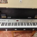 Stříbrný MIDI kontrolér Roland A-37 v černém transportním kufru s polstrováním. Na levé straně je nápis Roland A-37 MIDI KEYBOARD CONTROLLER a vprost…