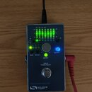 Kovový efekt pedál s nápisy PROGRAMMABLE EQ a SOURCE AUDIO. Na horní straně jsou čtyři zelené LEDy indikující úroveň signálu, ovládací knoflík a spín…