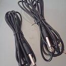 Dvě černé audio kabeláže s kovovými konektory typu jack. Kabely jsou svázány černými stahovacími pásky. Na povrchu kabelů nejsou viditelné žádné znač…