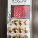 Zlaté ladicí mechanismy značky GROVER v originálním plastovém balení. Na horní části obalu je nápis GROVER LIFETIME GUARANTEE a červený štítek s text…