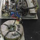 Fotografie zachycuje vnitřek elektronického zařízení, pravděpodobně zesilovače, s odkrytým šasi. Jsou vidět elektronické součástky, kabeláž a dva vel…