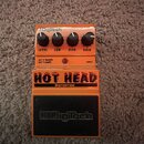Oranžový kytarový efekt s nápisem HOT HEAD DISTORTION a logem DigiTech v horní části i na spodním černém panelu. Na horní straně jsou čtyři černé oto…