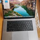Stříbrný notebook MacBook Pro s otevřeným displejem. Na obrazovce je vidět okno „O tomto Macu“ s nápisem MacBook Pro a v pozadí krajinná fotografie.…