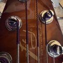 Detail zadní strany hředu kytary v hnědé barvě s kovovými ladicími mechanismy. Na povrchu je vidět zlaté logo a nápisy „Fokus Guitar Shop“ a „Made fo…