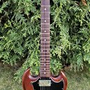 Elektrická kytara s hnědým trupem a tmavým hmatníkem. Na hlavě je zlatý nápis Gibson. Kytara má dva humbuckery, černý pickguard a čtyři ovládací knof…