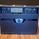 Zadní strana kytarového komba v černé barvě. Na horním panelu je nápis Randall RX75RG2, ovládací prvky pro EFFECTS LOOP a chladicí žebrování. V otevř…
