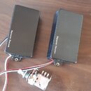 Dvě černé elektrické kytarové snímače s nápisem Seymour Duncan. Jsou vybaveny připojovacími kabely a k nim je přiložen jeden potenciometr s připojený…