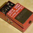 Červený kytarový pedál značky BOSS, model RC-3 Loop Station. Na horní straně jsou ovládací knoflíky, přepínače a nápisy OUTPUT A (MONO), OUTPUT B, IN…