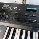 Černý digitální syntetizátor s nápisem YAMAHA DX7 III FD DIGITAL PROGRAMMABLE ALGORITHM SYNTHESIZER. V slotu pro kartu je zasunut modrá paměťová kart…