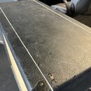 Detail horní části černého kytarového komba potaženého texturovaným vinylen. Povrch vykazuje známky opotřebení v podobě několika odírek a roztržení m…